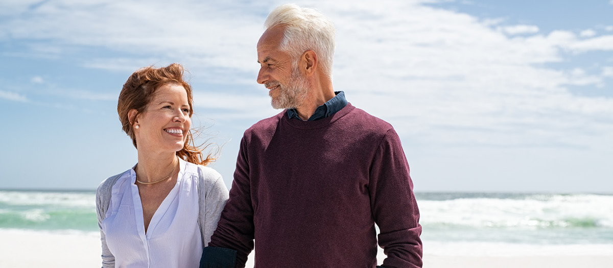 two adults walking on beach with tooth implants