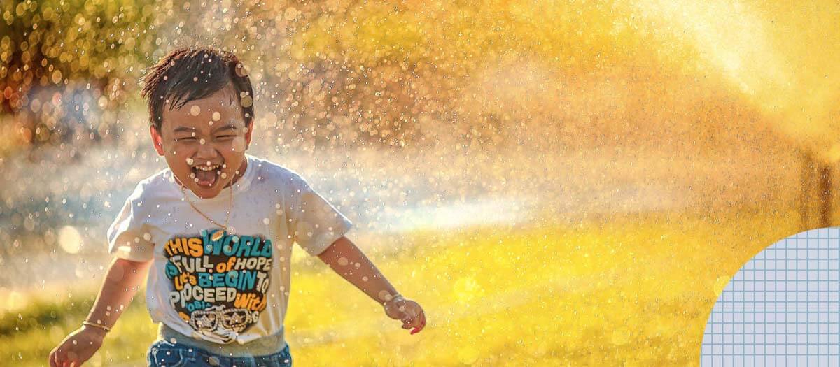 Boy running through sprinkler
