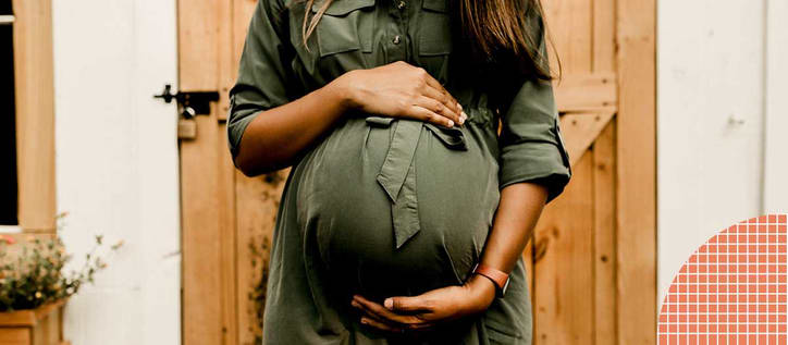 Pregnant woman standing and holding stomach